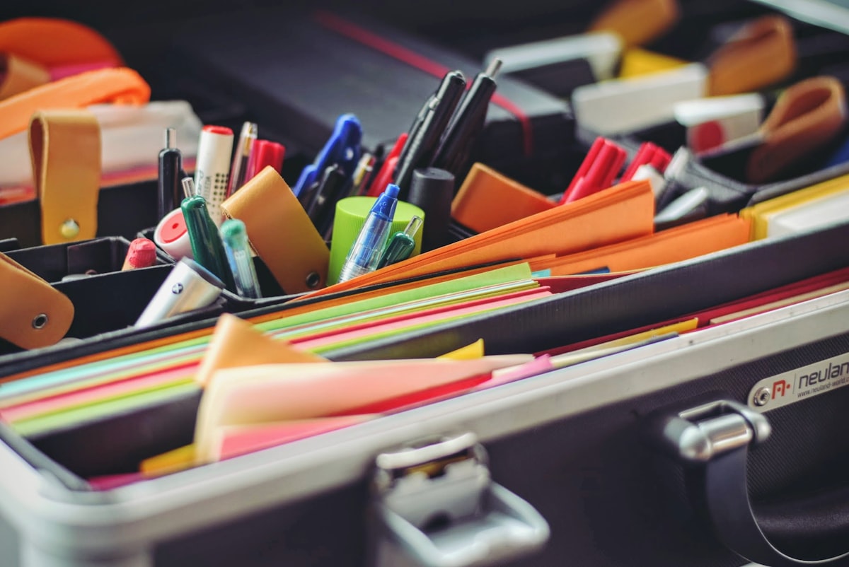 Assorted pens and colored papers in an organizer case