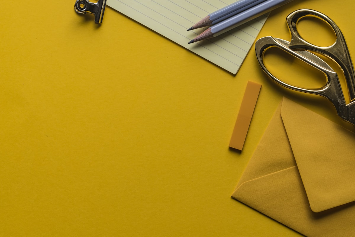 Scissors with envelope and pencils on a desk