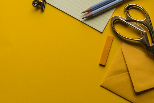 Scissors with envelope and pencils on a desk