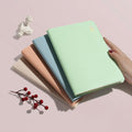 Sage green linen-covered A5 notebook held in hand